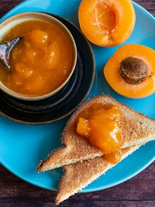 Top down shot of Apricot freezer jam on toast and in a bowl on a blue plate.