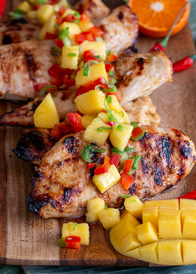 Mangoes sliced in cubes inside the flesh on a cutting board with the chicken.