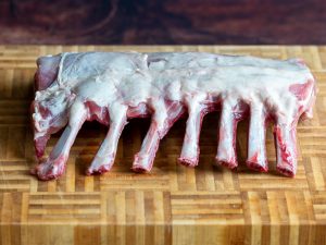 Frenched cut leg of lamb bones on a cutting board.