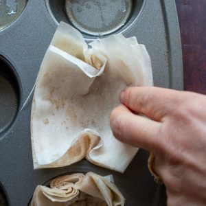 Phyllo dough layers getting pressed into the cupcake pan.