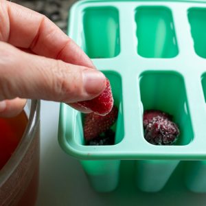 Frozen Berries getting added to the ice pop molds.