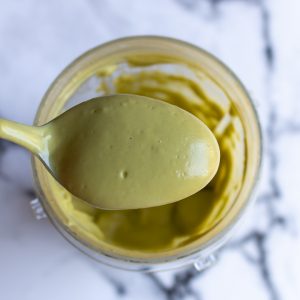 Spoonful of avocado mixture in a spoon showing it the consistency of creamy yogurt.