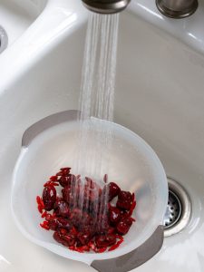 Red Dates and goji berries getting rinsed in the sink.