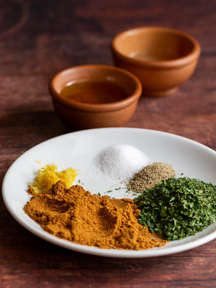 Moroccan Spices on a white plate with bowls of olive oil and lemon juice in the background.