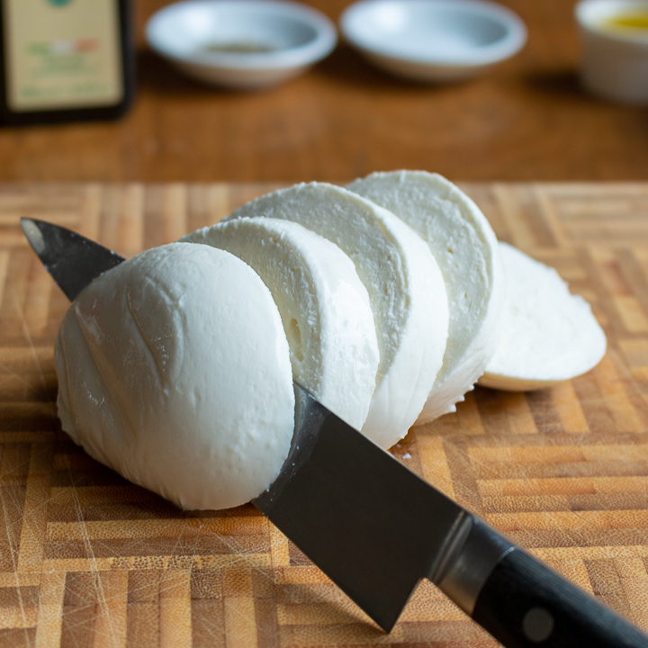 Fresh mozzarella cheese getting sliced. 