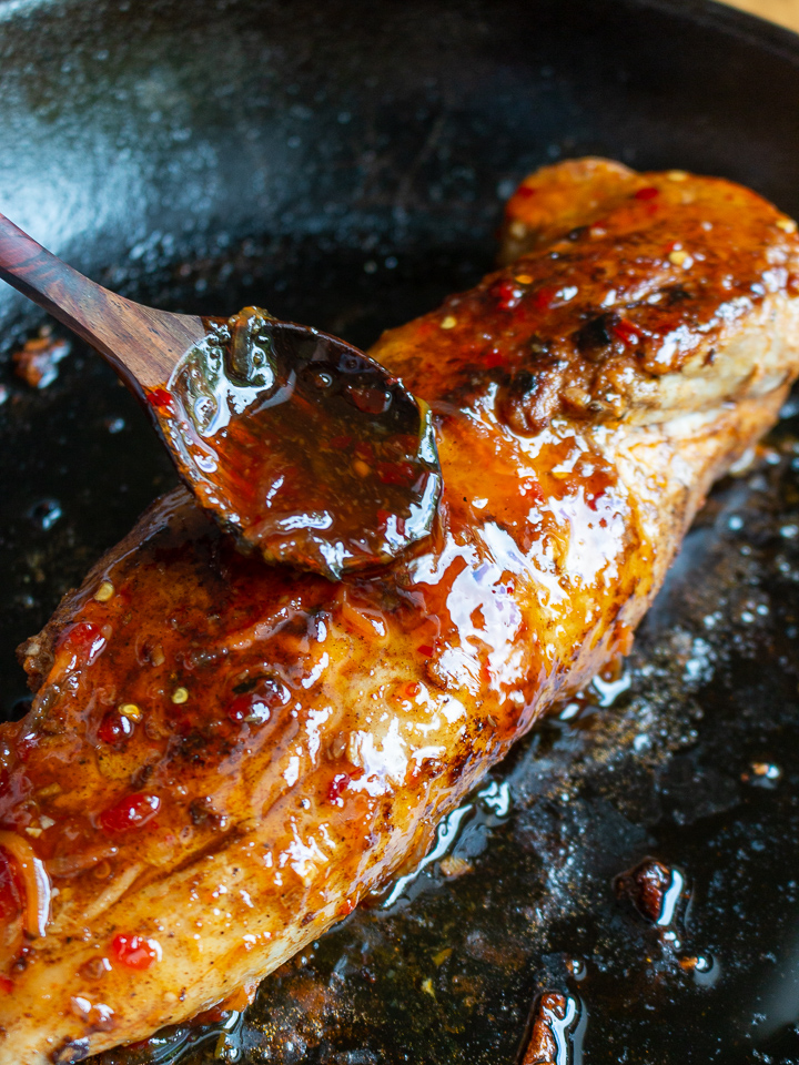 Spooning on Thai sweet chili sauce over pork tenderloin