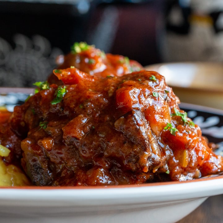 Close up shot of Italian beef oxtail stew in a black and white plate from Sienna, Italy.
