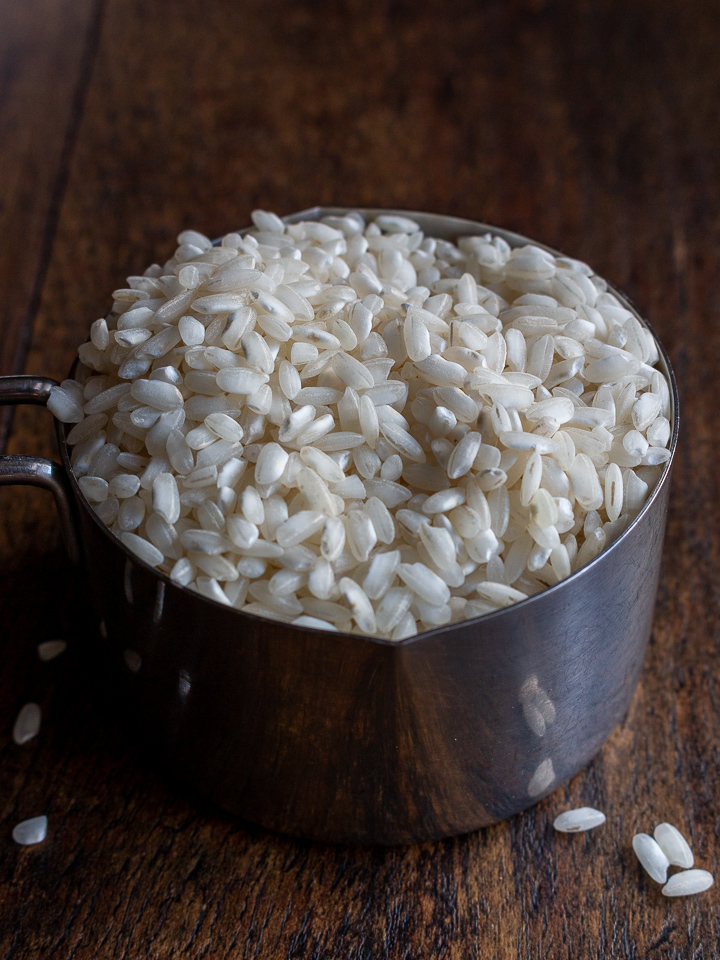 Arborio rice uncooked in a measuring cup.