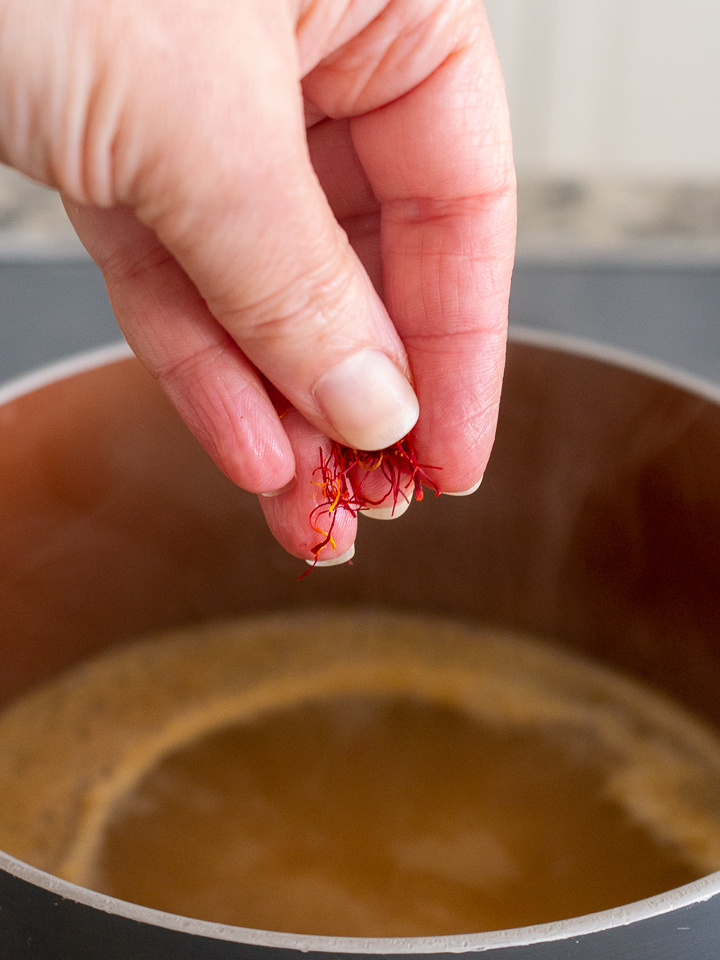 Pinch of saffron getting sprinkled into the chicken broth.