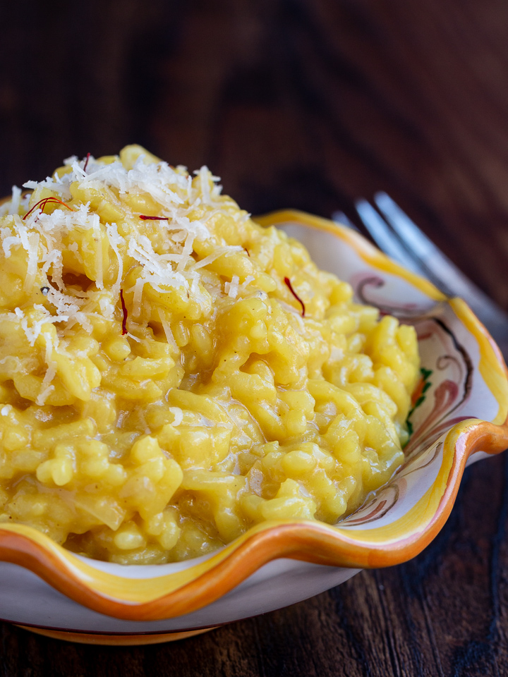Creamy Parmesan Risotto with Saffron in a white, yellow and orange hand painted Italian pottery plate.