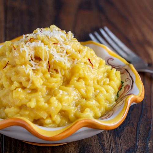 Creamy Parmesan Risotto with Saffron in a cute white and orange hand painted Italian pottery.