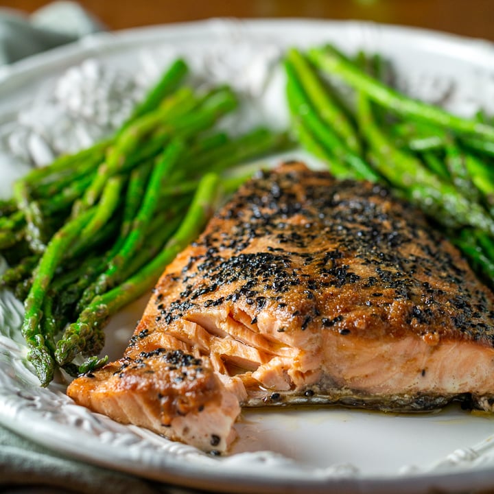 Baked miso salmon with asparagus on a white plate.