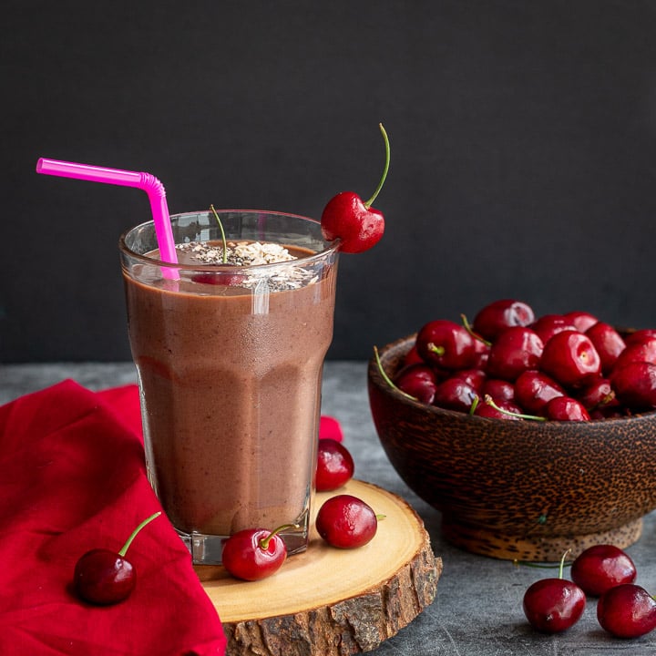 Chocolate Cherry smoothie on a wooden serving tray garnished with fresh cherries.