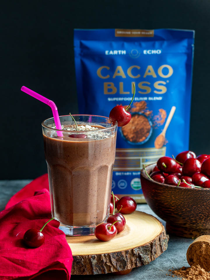 Cacao powder on display with cherries and a smoothie.