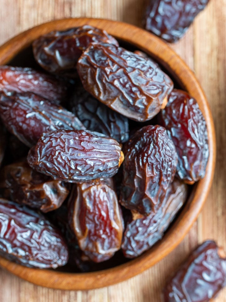 Whole Medjool dates in a wooden bowl.