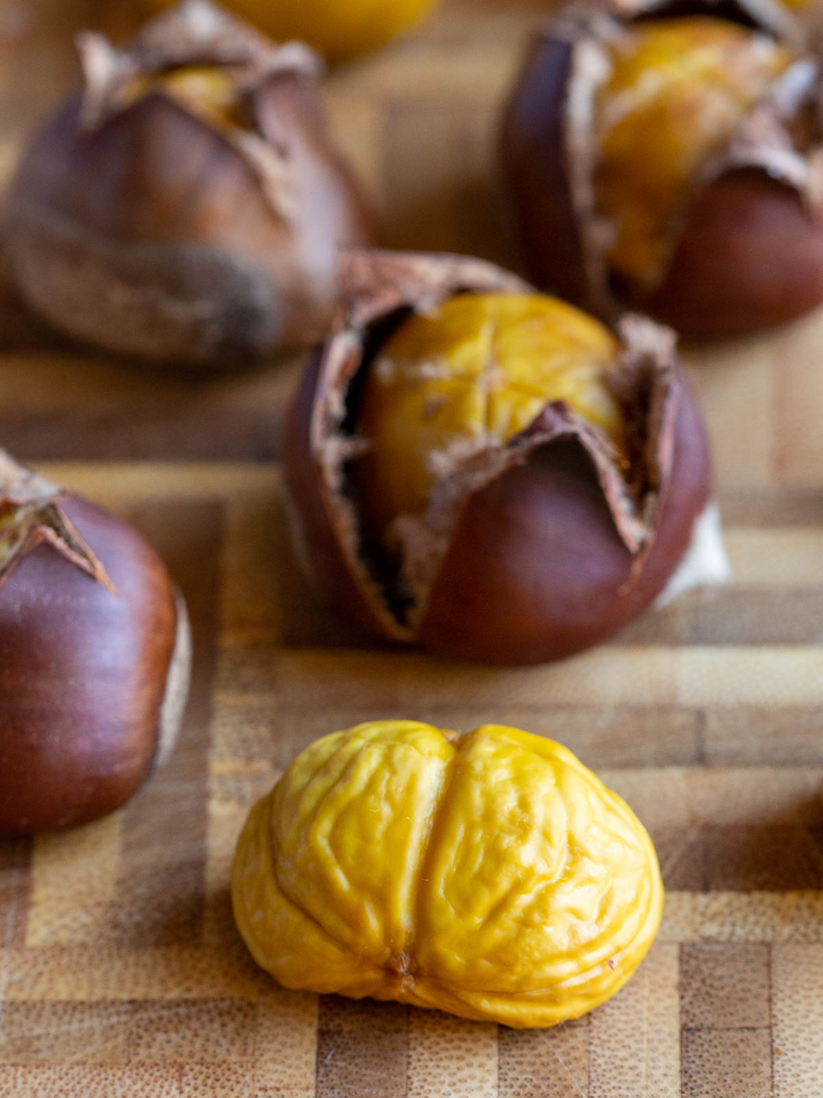 Peeled yellow chestnut with many in the background ready to be peeled.