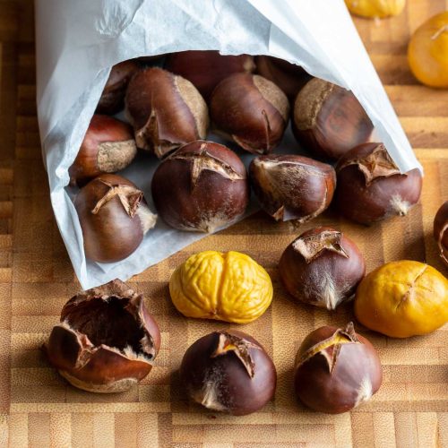 Roasted chestnuts falling out of a paper bags.