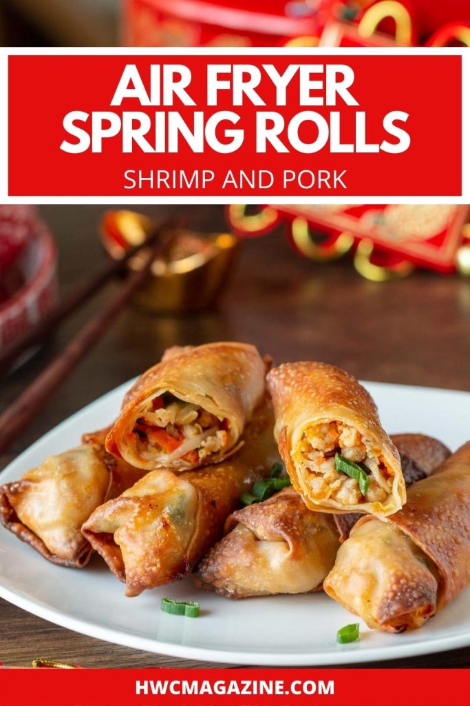 Air fryer spring rolls on a white plate with one cut in half with Chinese New Year decorations.