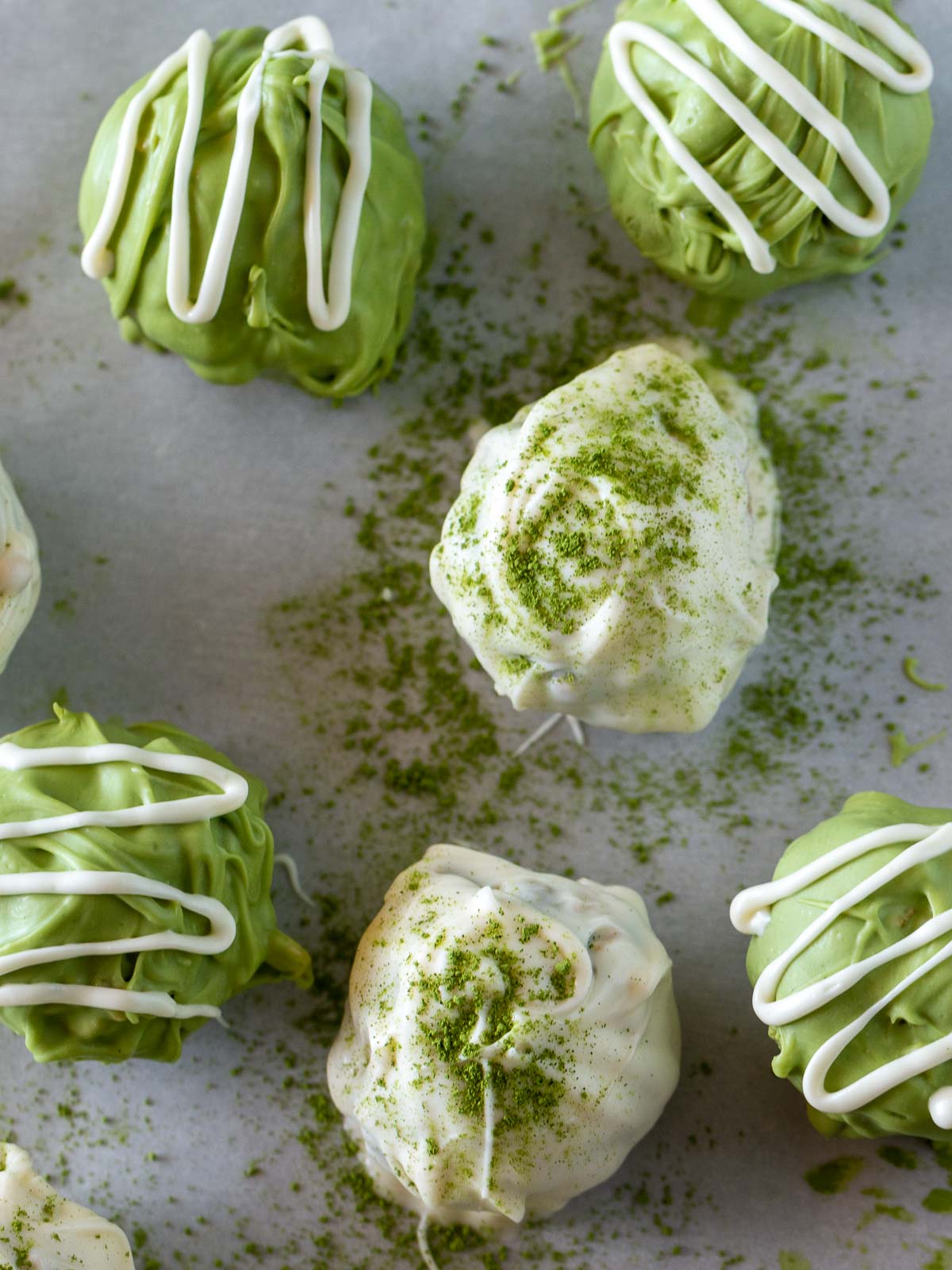 Decorated Matcha chocolate balls just dusted with matcha powder on a baking sheet.
