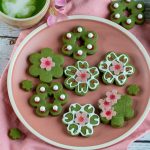 Sakura shortbread matcha cookies on a pink plate with a side of matcha latte.