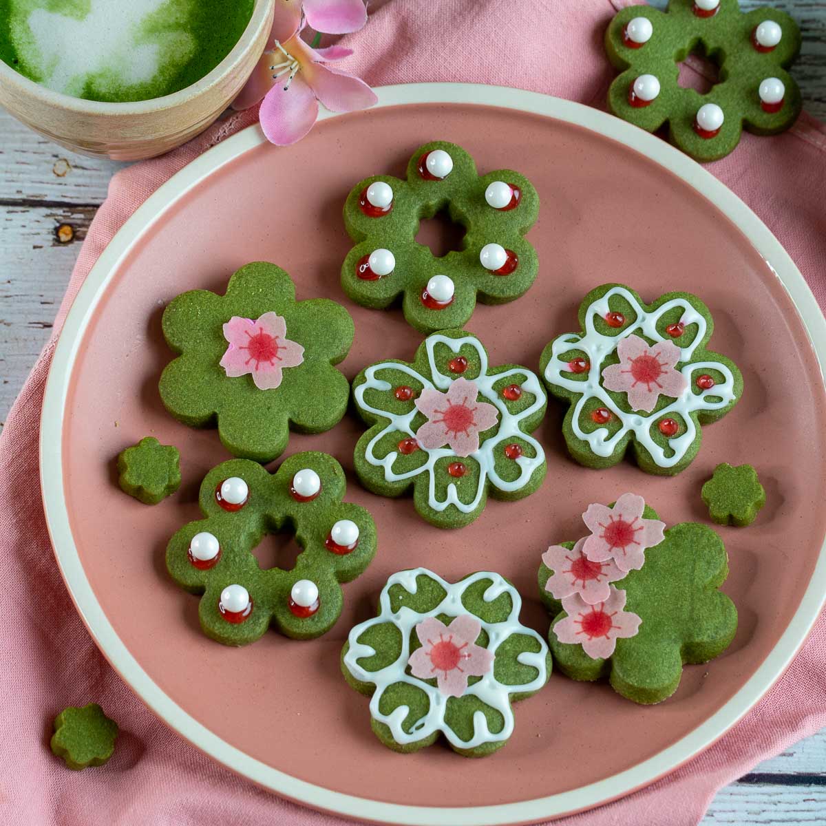 Sakura shortbread matcha cookies on a pink plate with a side of matcha latte.
