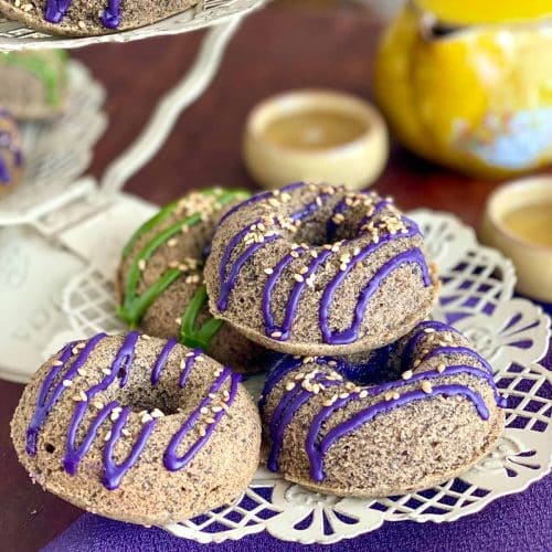 Ube and matcha glazed Baked black sesame mochi donuts on a white plate.