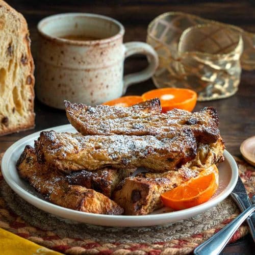 Panettone air fryer French toast sticks dusted with powdered sugar on a white plate.