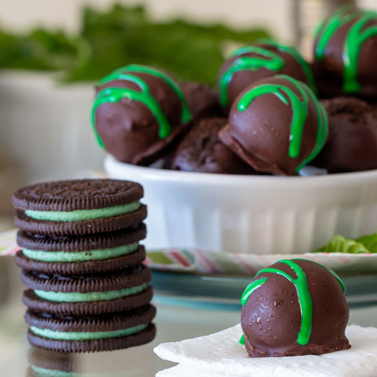 Mint Oreo balls made without cream cheese in a white bowl with a stack of Oreo biscuits.