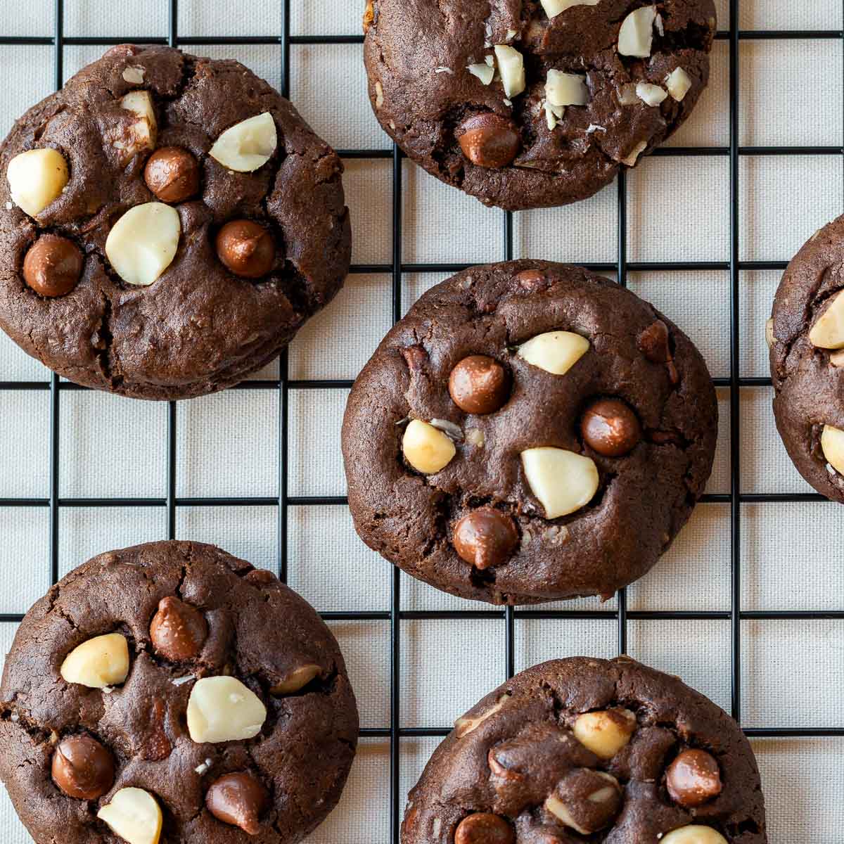 Fudgy dark chocolate macadamia nut cookies cooling on a rack. 