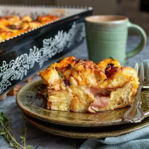 A slice of savory breakfast bread pudding on a green plate with a cup of coffee in a green mug,