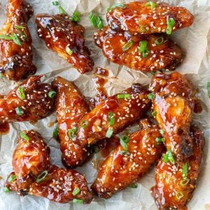 Gluten free baked General Tso's chicken wings served up on a parchment paper lined plate.