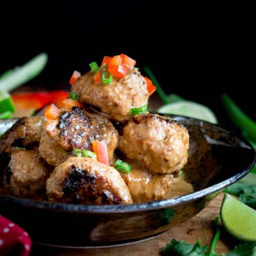 A bowl of Thai low carb turkey meatballs in a coconut red curry sauce in a black bowl.