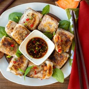 Gluten-free rice paper dumplings on a white plate with dipping sauce.