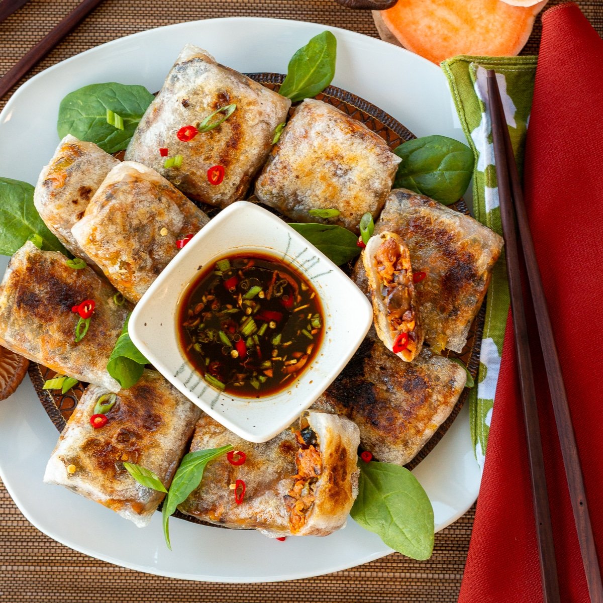 Gluten-free rice paper dumplings on a white plate with dipping sauce.