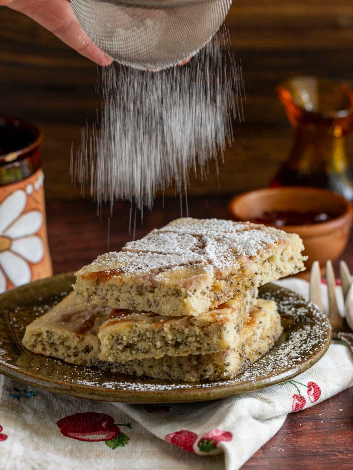 Sprinkling powdered sugar over a stack of flapjacks. 