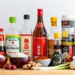 Many essential Asian pantry staples sitting out on a wooden table.