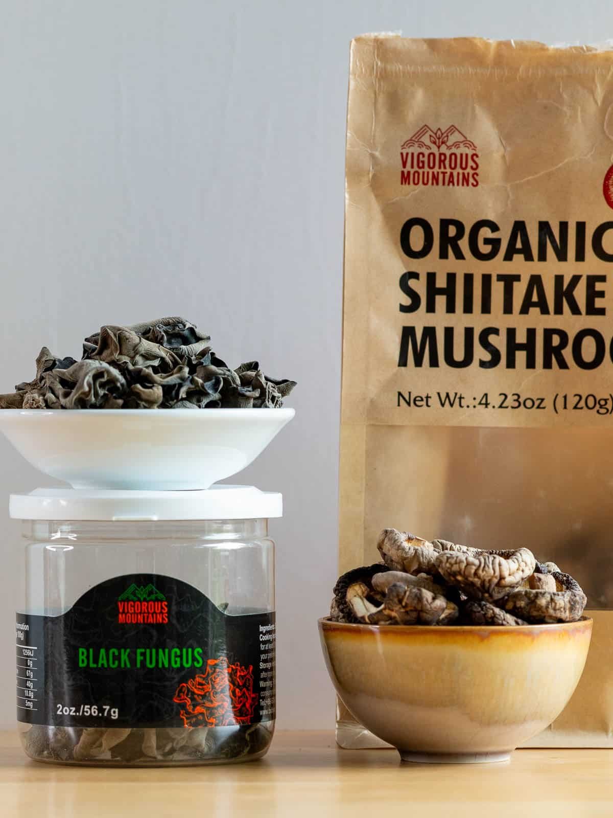 Dried shiitake and wood ear mushrooms in dishes with the packages behind.
