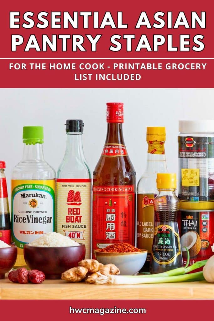 Essential Asian pantry staples like sauces, spices and aromatics laid out on a wooden table.