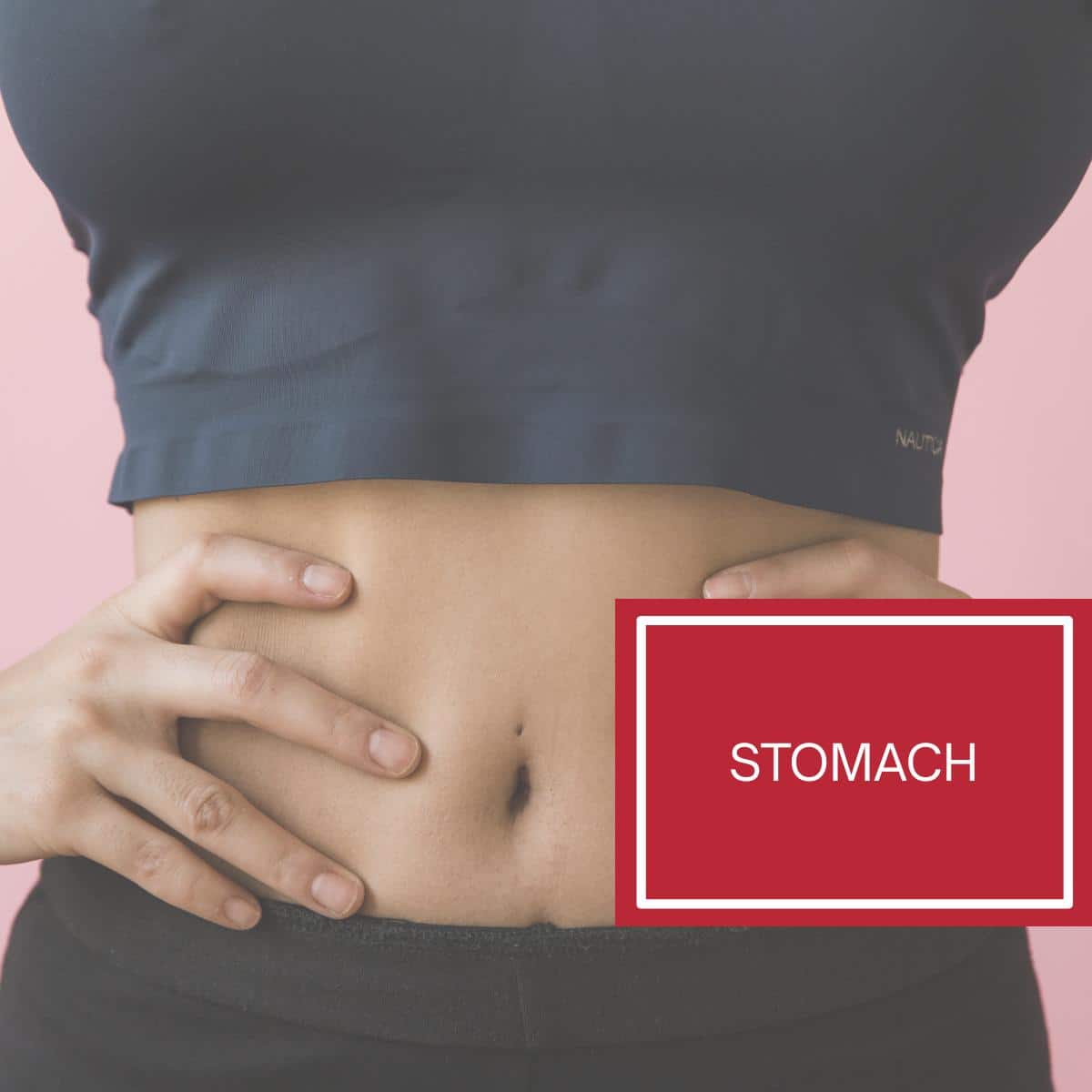 A woman in a yoga outfit with her hands on her hips showing her stomach gut area. 