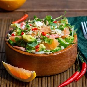 Thai Crab avocado salad in a big wooden bowl garnished with grapefruit vinaigrette.