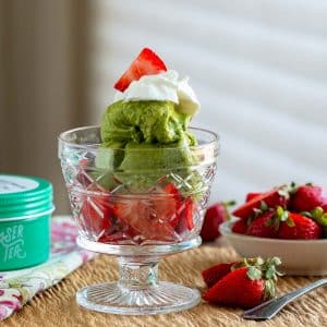 Matcha banana ice cream layered with fresh strawberries in a clear dessert cup.