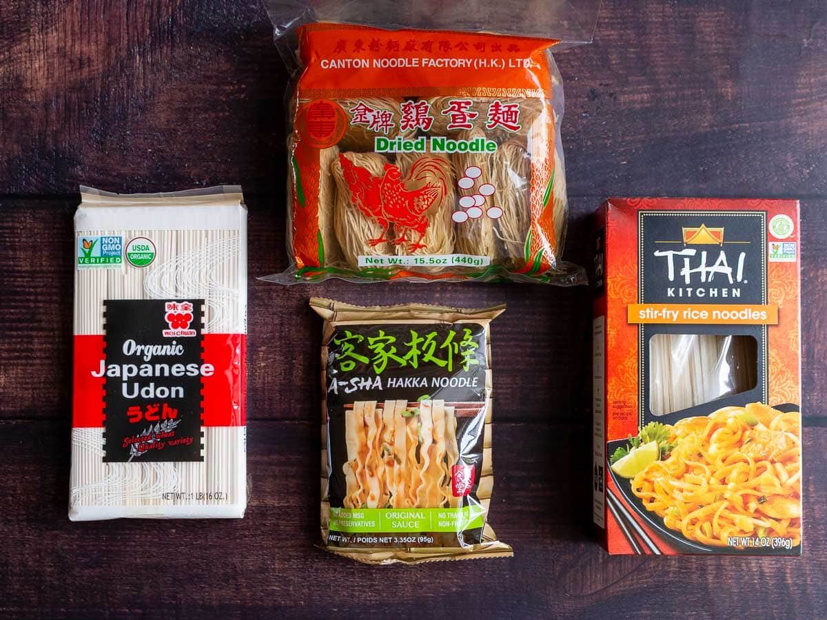 Different kinds of Asian noodles laid out on a wooden table.