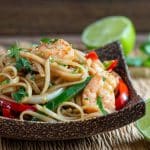 Saucy Asian shrimp and noodle stir fry in a wooden bowl.