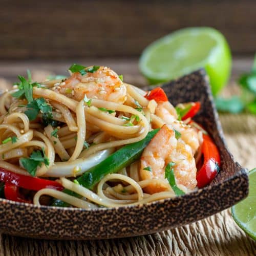 Saucy Asian shrimp and noodle stir fry in a wooden bowl.