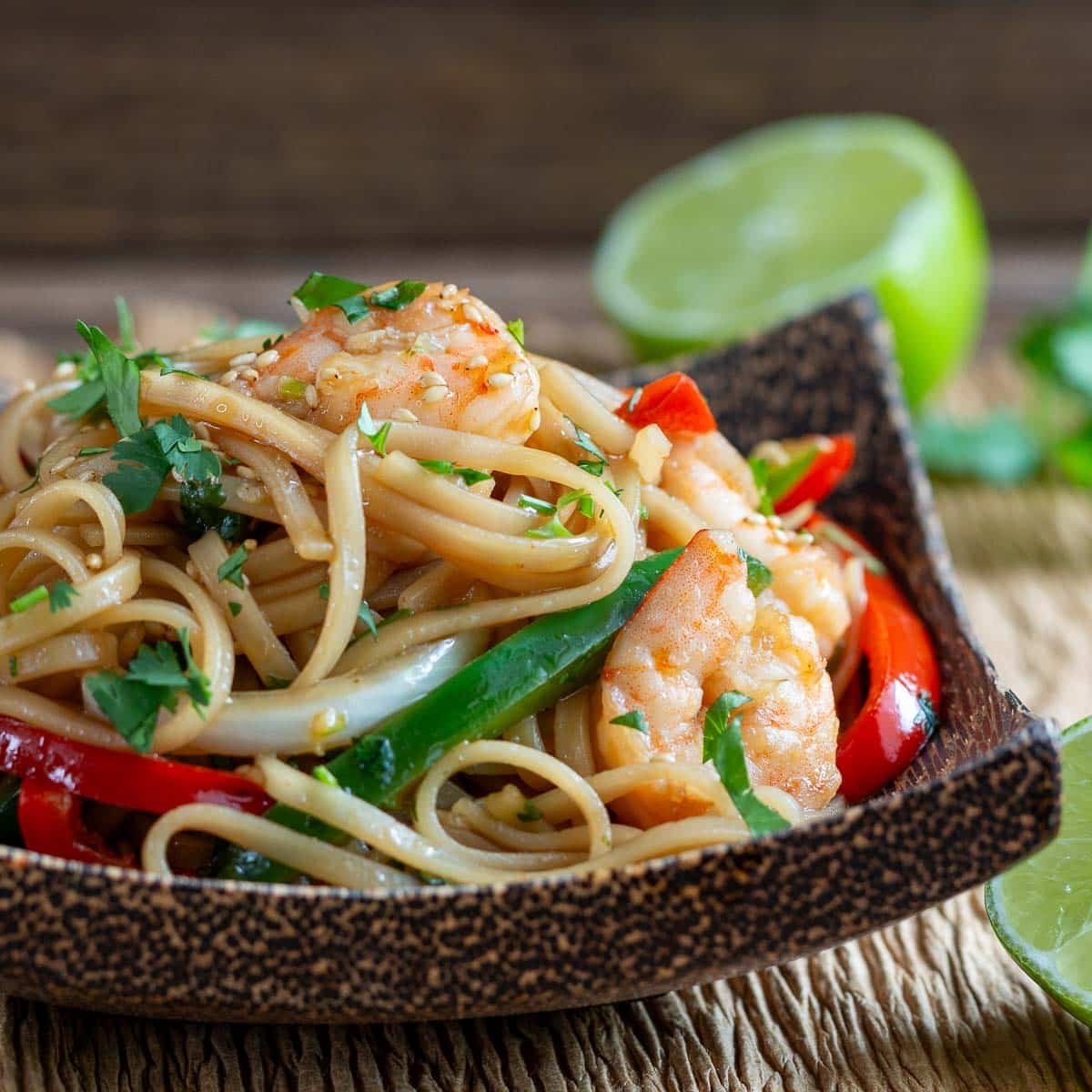 Saucy Asian shrimp and noodle stir fry in a wooden bowl.