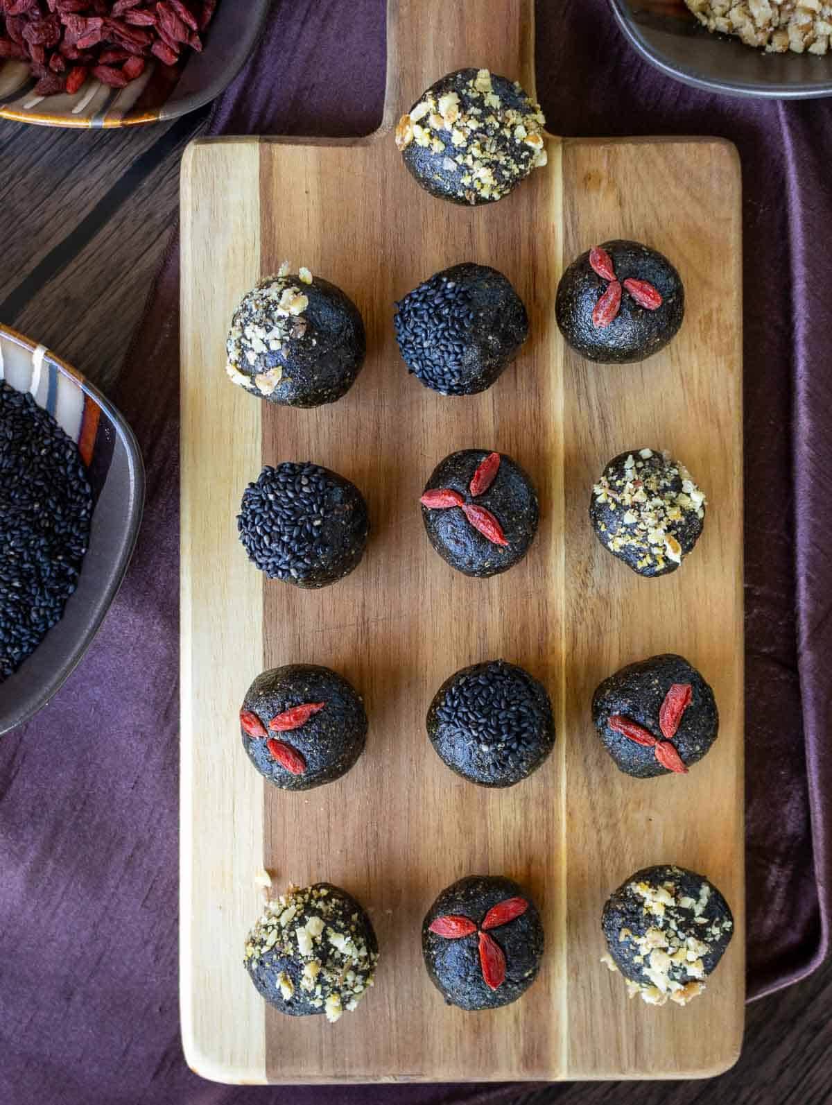 Thirteen kidney yin supporting energy bites on a wooden serving board.