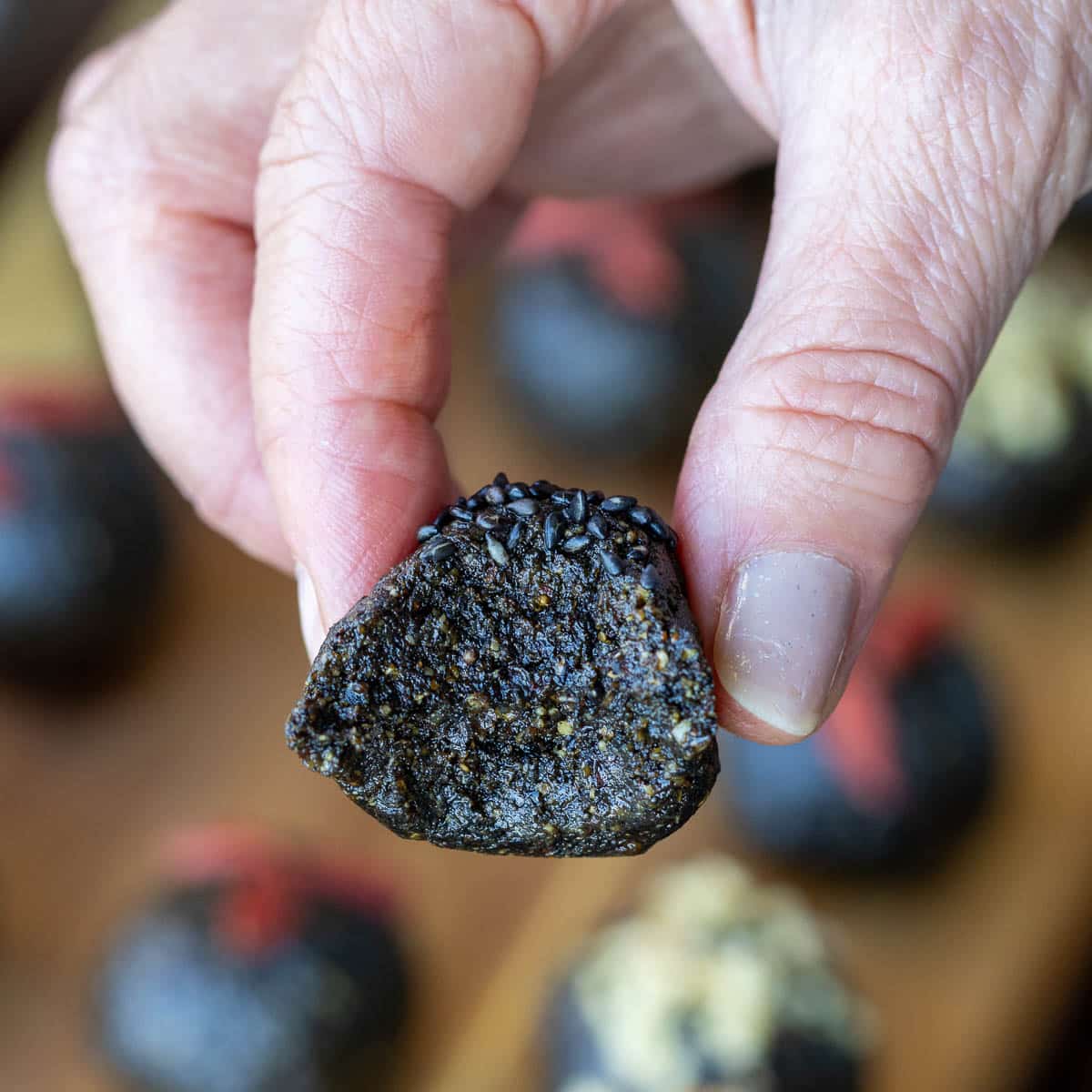 Biting into a black sesame walnut bliss ball showing how chewy they are.