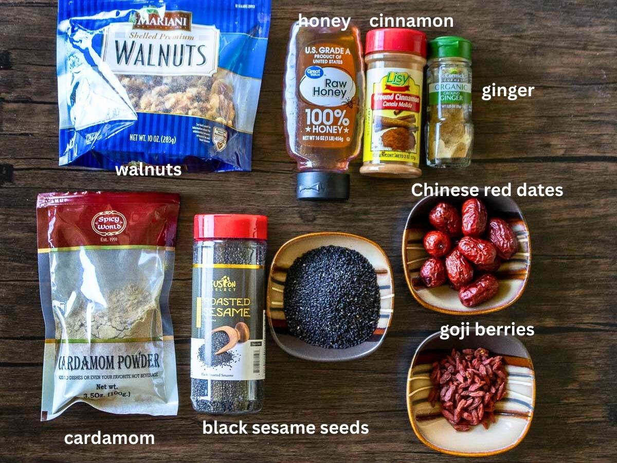 Ingredients to make black sesame balls with goji berries, jujubes amd warming spices on a brown background.
