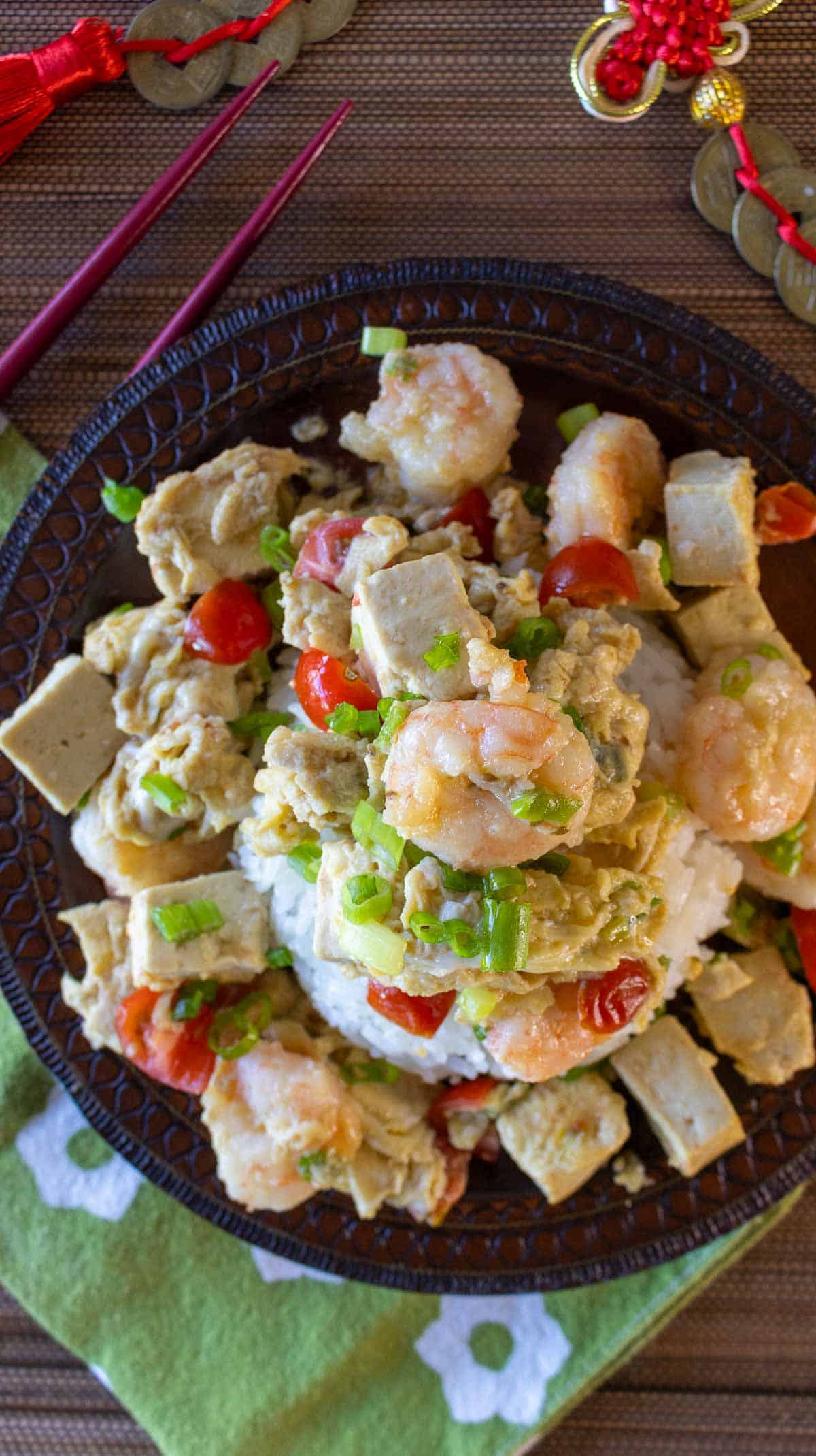 Looking top down on to a plate of scrambled eggs and shrimp over rice with Chinese New Year decorations.